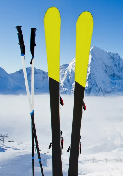 Bâtons et ski plantés au sol sur un fond de montagne enneigée.
