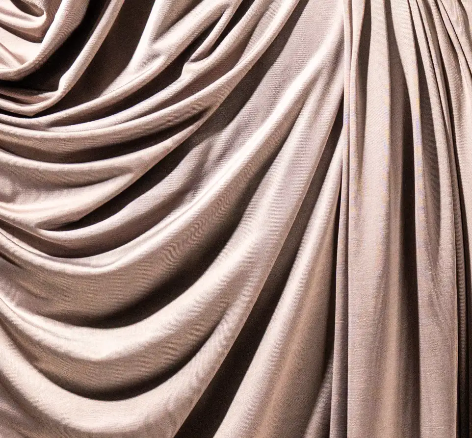 Gros plan sur la texture d'un tissu jersey satiné gris aux reflets brillants.