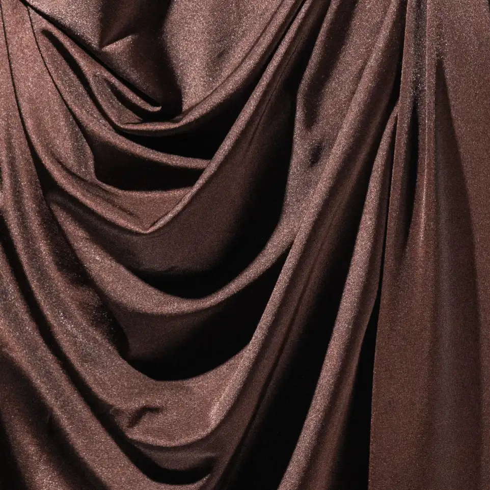 Gros plan d'un tissu en jersey satiné marron à l'aspect brillant, offrant un tombé fluide et une finition soyeuse.